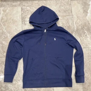 Polo Ralph lauren hoodie - Säljer en snygg mörkblå hoodie från Polo Ralph Lauren med dragkedja och huva. Storlek L