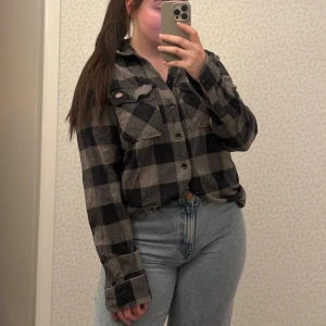 Rutig skjorta från Dickies - Säljer en snygg rutig skjorta från Dickies i svart och grått. Skjortan har långa ärmar och knappar framtill. Perfekt för en avslappnad stil med en klassisk look. Passar bra till jeans eller chinos.