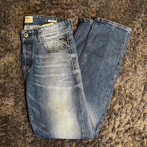 Blå jeans från Replay - Snygga blå jeans från Replay med en klassisk femficksdesign och diskreta slitningar för en trendig look. Det är modell grover för den som inte gillar alldeles för tajta men inte för pösiga jeans heller i nytt skick! Storlek 28W/30L, pris kan diskuteras vid snabb affär! Hör av er vid minsta lilla!😊🤩