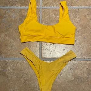 Gul bikini - Trendig gul bikini med sportig topp och hög midja. Perfekt för soliga dagar på stranden eller vid poolen. Den klara färgen ger en fräsch och somrig look.