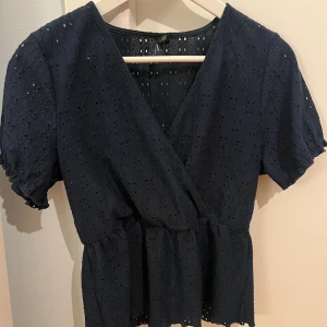 Mörkblå omlottblus - Snygg mörkblå omlottblus med korta ärmarfrån Vero Moda.  Perfekt för både vardag och speciella tillfällen. Passar även väldigt bra i sommar💗