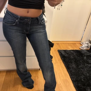 Blå jeans med broderad detalj - Snygga blå jeans från Guess med broderade detaljer på bakfickorna samt glittriga stenar. De har en klassisk femficksdesign och en bekväm passform. 