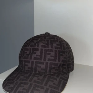 Svart Fendi keps osäljbara i butik  - Snygg svart keps från Fendi med ett distinkt mönster. Kepsen har en justerbar rem baktill för perfekt passform. Perfekt för att ge din outfit en lyxig touch. Har bytt klädstil och därför säljer jag denna kepsen till er som gillar snygga kepsar som matchar din stil!!!