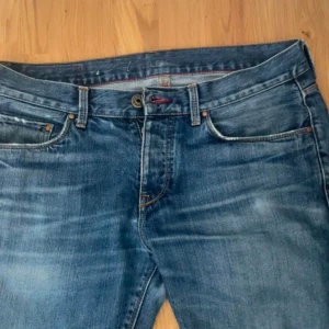 Blå jeansbyxor Tommy hilfiger - Snygga blå jeans med klassisk femficksdesign och knappgylf. De har en lätt tvättad look och är perfekta för en avslappnad stil. Passar bra till både t-shirt och skjorta.