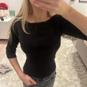 Svart ribbad topp - Snygg svart ribbad topp med trekvartsärm. Perfekt för en stilren look. Passar bra till både jeans och kjol.