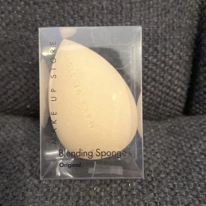 Beige Blending Sponge från Make Up Store - Säljer en beige blending sponge från Make Up Store. Perfekt för att applicera foundation och concealer jämnt. Den droppformade designen gör det enkelt att nå alla ansiktskonturer. Kommer i en genomskinlig förpackning. Helt ny 