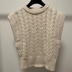 Stickad väst från NA-KD - Säljer en snygg beige stickad väst från NA-KD. Västen har ett fint stickat mönster och är tajtare runt midjan. Bara att skriva om fler bilder önskas💕