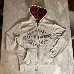 Grå Ralph Lauren zip hoodie  - Skick: 8/10. Tröjan är i väldigt bra skick och har inga defekter. Från märket Ralph Lauren. Om du är osäker på om det kommer att passa kan du alltid fråga om mått! 