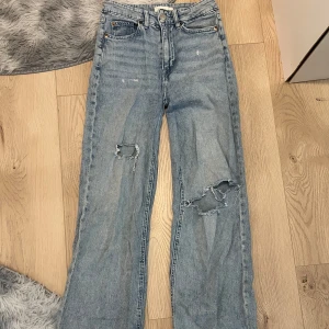 Jeans med håliga knän - Raka vida ljusblå jeans med håliga knän. Säljer då jag har växt ur dom. Storlek 34 (ej jeansstorlek)