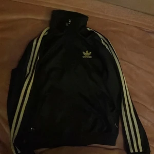 Svart och guldig adidas zipup - svart och guldig adidas zipup i nyskick, storlek small