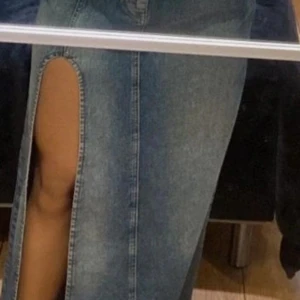 Jeanskjol med slits - Snygg jeanskjol från Bershka i en klassisk blå denimfärg. Kjolen har en trendig slits framtill som ger en cool look. Perfekt för att styla med olika toppar och accessoarer.