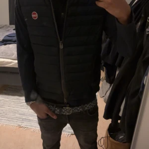 Mörkblå quiltad väst från Colmar - Säljer en snygg mörkblå quiltad väst från Colmar. Västen har en dragkedja framtill och ett stilrent märke på bröstet. Perfekt för lager-på-lager under kyligare dagar. 