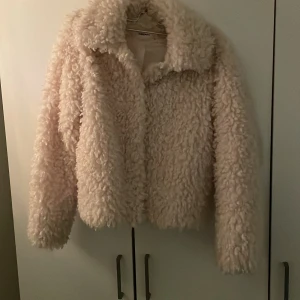 Beige teddyjacka från Kappahl - Mysig beige teddyjacka från Kappahl i storlek XS. Jackan har en fluffig och varm design med långa ärmar, perfekt för kalla dagar