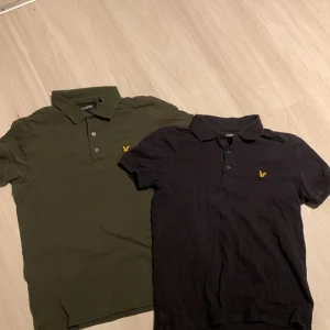 Två pikétröjor från Lyle & Scott - Säljer två snygga pikétröjor från Lyle & Scott. En i svart och en i olivgrön, båda med korta ärmar och klassisk krage. Tröjorna har en liten gul logotyp på bröstet och knappar framtill. Perfekta för en stilren look! Den olivgröna pikén är i storlek S och den Svarta är i storlek Xs!