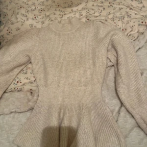 Beige stickad tröja från Studio - Säljer en stilren beige stickad tröja från Studio. Tröjan har en figurnära passform med långa ärmar och en ribbad struktur. Perfekt för kyligare dagar.