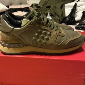  Valentino rockrunners - Snygga olivgröna sneakers från Valentino med coola nitar på sidorna. Skorna har en kombination av mocka och skinn, vilket ger dem en unik look. De har snörning och en bekväm sula som passar perfekt för vardagsbruk. Storlek 37.5 har vanligtvis 39 men de passar mig endå 