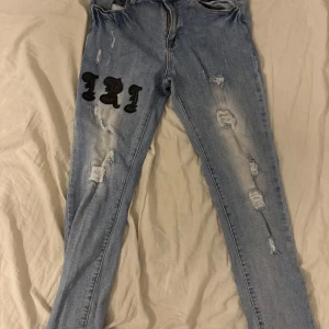 Blå slim jeans med slitningar från Amiri - Blåa slim jeans från Amiri med  slitningar och tryck på benen. 