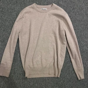 Beige tröja från Zara - Säljer en stilren beige tröja från Zara. Tröjan har långa ärmar och en rund halsringning med ribbade kanter. Perfekt för en avslappnad och snygg look.