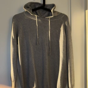 Grå merinoull tröja - Säljer en stilren grå merinoull tröja i huvan. Tröjan har långa ärmar och är perfekt för en avslappnad look. Den är mjuk och bekväm, idealisk för kyligare dagar. Storlek XS och skick 9/10