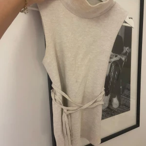 topp zara - Snygg beige ärmlös topp med knytband i midjan. Tröjan är från Zara! (Det är lite smink vid kragen med det går bort i tvätten innan jag skickar den). Köpt för något år sedan men sparsamt använd. Storlek S. Tröjan går att använda med och utan knyt