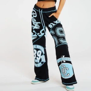 Byxor från Jaded london - Coola svarta byxor med blåa tryck och textdetaljer. Byxorna har en loose passform och är dekorerade med stora grafiska element och text. De har en snörning i midjan för justerbar passform. Är använda ett fåtal gånger å passar väldigt bra💗