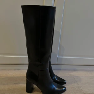 Svarta höga spetsiga stövlar med klack - Eleganta svarta höga stövlar med hög klack och spetsig tå. Perfekta för en stilren look.