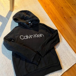 2x hoodie från Calvin Klein - 449:- - Två snygga hoodies från Calvin Klein. Den ena är svart med vit logga på bröstet, och den andra är grå med en stor 'ck' logga i svart.  Båda storlek: Small. Säljs i paketpris