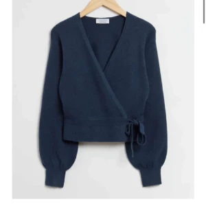 Mörkblå omlottkofta från & Other Stories - Säljer en stilren mörkblå omlottkofta från & Other Stories. Koftan har långa ärmar och knytband i midjan för en justerbar passform. Perfekt för kyligare dagar.