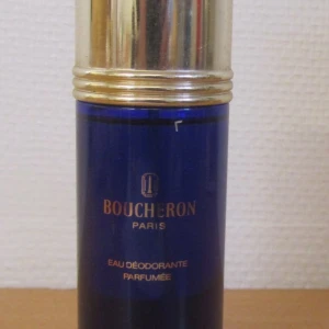 Blå parfym från Boucheron 100 ml, full flaska - Elegant blå parfymflaska från Boucheron Paris med gyllene detaljer. Flaskan har en lyxig design och innehåller Eau Déodorante Parfumée. Perfekt för den som söker en sofistikerad doftupplevelse.