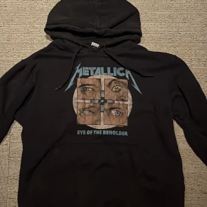 Svart Metallica hoodie från Amplified - Säljer en svart hoodie från Amplified med Metallica-tryck och texten 'Eye of the Beholder'. 