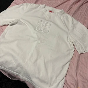 Hugo Boss använd 1 gång - Snygg vit t-shirt från Hugo med upphöjd logotyp på framsidan. Perfekt för en stilren look. Tillverkad i mjukt material för extra komfort. Säljer pga den är för liten för mig, den är använd 1 gång och är som ny