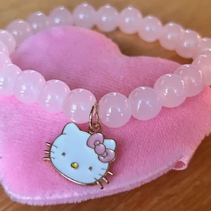 Elastiskt armband med Hello Kitty! - Sött elastiskt armband med rosa pärlor och Hello Kitty-berlock. Nytt! 