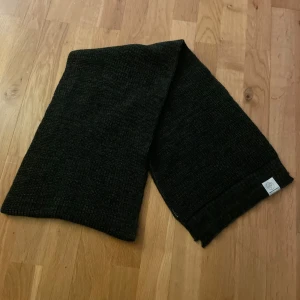 Scarf Pelle P - Snygg svart stickad scarf från Pelle p. Perfekt för att hålla dig varm under kyliga dagar. Den har en enkel och stilren design som passar till det mesta.