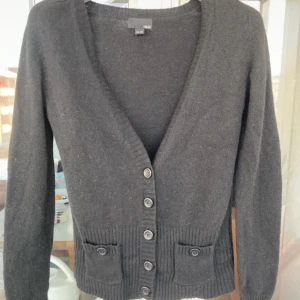 Svart kofta från H&M - Säljer en stilren svart kofta från H&M med knappar framtill och två fickor. Koftan har långa ärmar och ribbade detaljer vid ärmslut och nederkant. Perfekt för kyligare dagar! 💗🥰