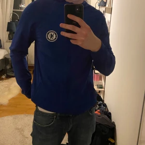 Blå träningsjacka från Nike chealsea - Säljer en blå träningsjacka från Nike med Chelsea FC-logga på bröstet. Jackan har dragkedja och långa ärmar, perfekt för fotbollsträning eller vardagsbruk.