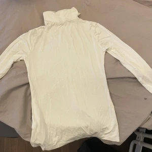 Vit polotröja - Säljer en stilren vit polotröja med långa ärmar. Perfekt för kyligare dagar och enkel att matcha med olika outfits.