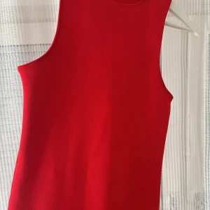 Röd ärmlös klänning från ZARA - Snygg röd ärmlös klänning i en stilren design. Perfekt för en elegant look med sin figurnära passform och enkla snitt.