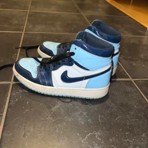 Nike Air Jordans i blå och vit - Snygga Nike Air Jordans i en fräsch kombination av blått och vitt. Skorna har klassisk snörning och en hög design som ger extra stöd. EJ ÄKTA, i använt skick och de är creasade där framme. Men med en tvätt tror jag att de blir riktigt fina. 