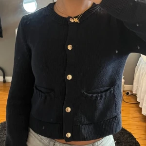Svart kofta med guldknappar - Snygg marinblå kofta med guldknappar framtill. Den har långa ärmar och två fickor. Perfekt för en stilren look.