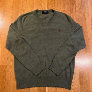 Ralph Lauren tröja - Säljer en stilren grön tröja från Polo Ralph Lauren med v-ringning och broderad logotyp på bröstet.   Materialet är merino ull som är riktigt skönt o varmt nu till vintern. Skick 9/10. Mvh PastPerfect