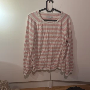 Rosa och vit randig tröja från ONLY - Säljer en söt och bekväm rosa och vit randig tröja från ONLY. Tröjan har långa ärmar och en rund halsringning, perfekt för en avslappnad stil. Den är gjord i ett mjukt material som känns skönt mot huden.