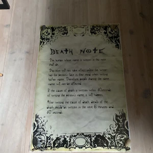 Death Note poster - Stor poster med texten 'Death Note' på framsidan. Boken har ett dekorativt mönster i svart och vitt runt kanterna och innehåller regler skrivna på engelska. Perfekt för fans av serien som vill ha en unik samlarobjekt.