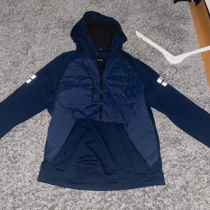 Mörkblå Cardigan/jacka med dragkedja - Snygg mörkblå cardigan/jacka med dragkedja och huva. Jackan har långa ärmar och en quiltad framsida. Perfekt för en casual look. Kostar 2500 ny säljer för 750.  pris kan diskuteras vid snabb affär.