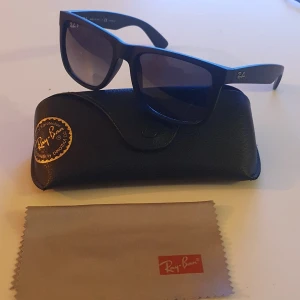 Svarta solglasögon Ray-Ban Justin - Snygga svarta Ray-Ban Justin solglasögon, modell RB 4165. De har en klassisk design med breda skalmar och mörka linser. Perfekta för en stilren look. Levereras med originalfodral och putsduk.