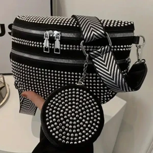 Svart axelväska med nitar - Snygg svart axelväska dekorerad med glittriga nitar och ett matchande runt fodral. Väskan har flera dragkedjor och ett brett, mönstrat axelband i svart och vitt. Perfekt för att ge en edgy touch till din outfit.