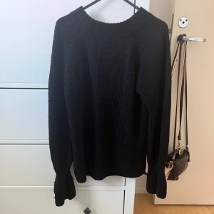 Svart stickad tröja - Säljer en mysig svart stickad tröja som är perfekt för kyliga dagar. Tröjan har långa ärmar och en ribbad struktur som ger den en klassisk look. Den är i bra skick och passar till både vardag och lite finare tillfällen. Perfekt att matcha med jeans eller kjol!