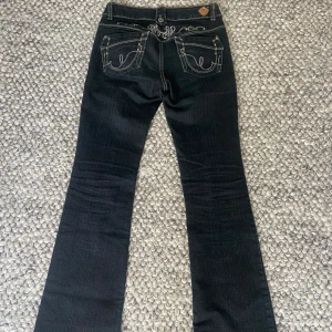 Lågmidjade jeans - Snygga jeans från Jane Norman. Lågmidjade bootcut, med broderier på rumpan. De är mörkblå men kan se svarta ut ibland. Skulle säga att de är en storlek s/36. De är även väldigt långa, passar mig bra som är 172