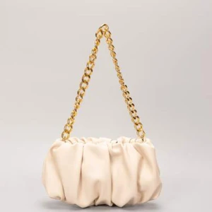 Beige axelväska med guldkedja - Säljer en superfin beige axelväska med en snygg guldkedja som axelrem. 70kr