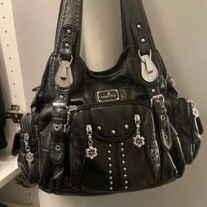 Snygg angels kiss väska -  ANGEL KISS VÄSKA Säljer eftersom det inte är min stil längre men den är fortfarande så sjukt snygg.  inga defekter och passar bra med allt!! Längre band ingår även. Tveka inte att höra av er vid frågor om fler bilder osv! 🩷