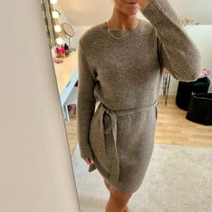 Stickad klänning - Supermysig brun stickad klänning med knytband i midjan. Storlek M men passar även XS-S. Stretchig och mjuk. Är 167 cm lång och vanlig S-M.